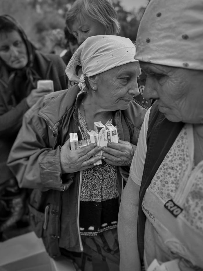 grayscale-photo-of-elderly-women-receiving-medicine-boxes-13566304 Elderly women receiving medical aid in Ukraine, highlighting humanitarian efforts.